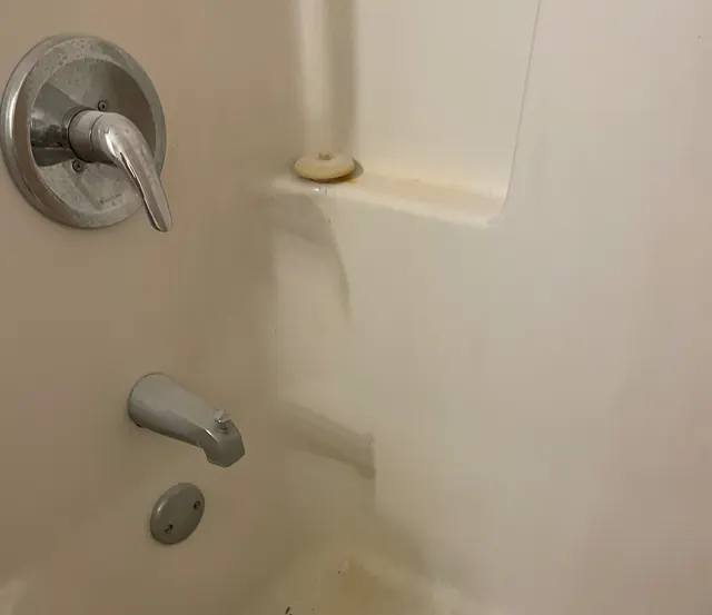 Before: A bathtub surround with yellow stains around the fixtures.