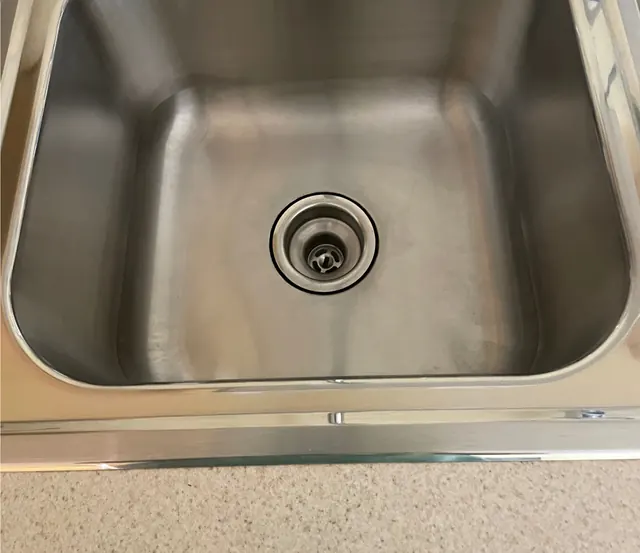 After: The same stainless sink, bright, with a polished faucet.